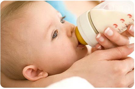 Ребенок пьет с бутылочки молочную смесь