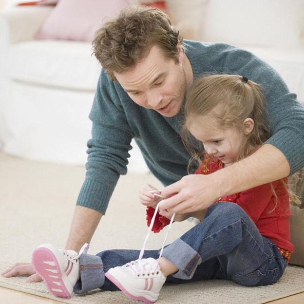 Ребёнок с отцом завязывают шнурки