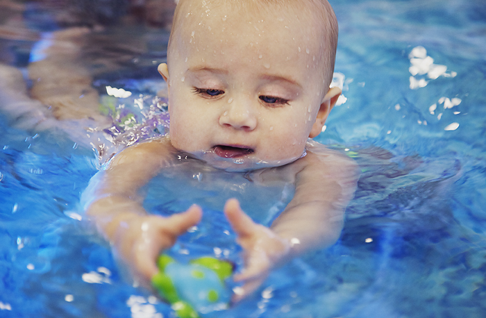 Малыш в воде пытается схватить игрушку